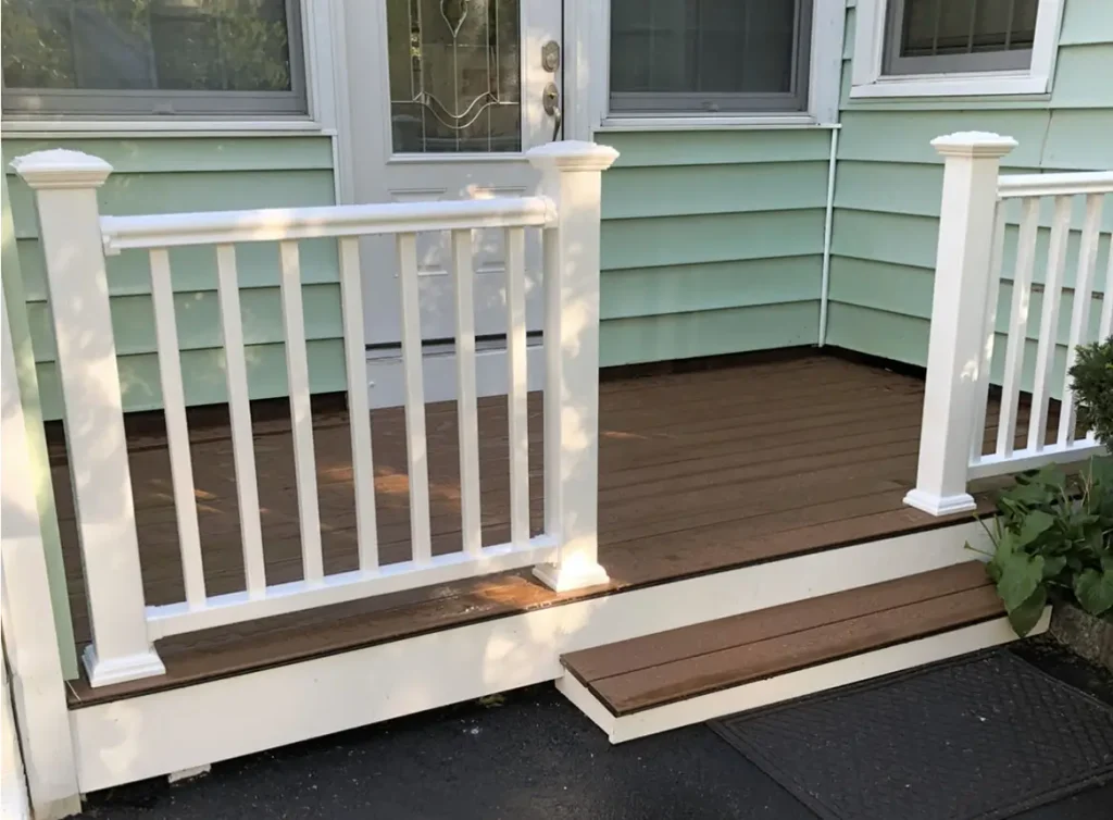 Front yard deck with hardwood floor. The single story home has lime green siding.